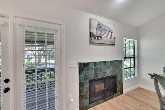 interior space with a tiled fireplace and wood-type flooring