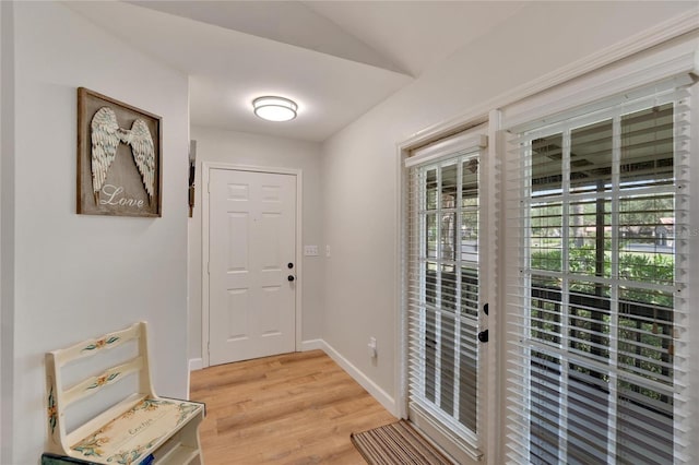 doorway featuring vaulted ceiling and light hardwood / wood-style flooring