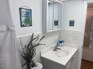 bathroom featuring toilet, tile walls, and vanity