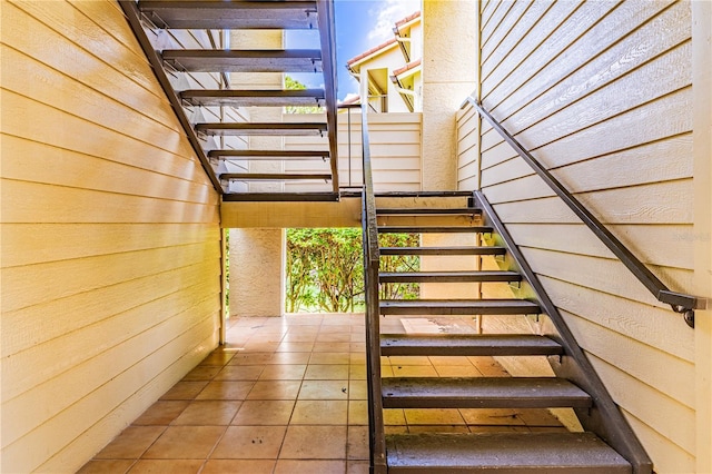 stairway featuring tile patterned flooring and wood walls