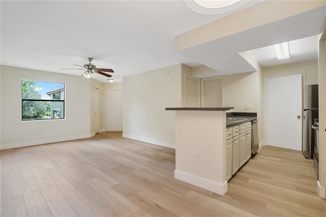 kitchen with appliances with stainless steel finishes, kitchen peninsula, sink, and light hardwood / wood-style flooring