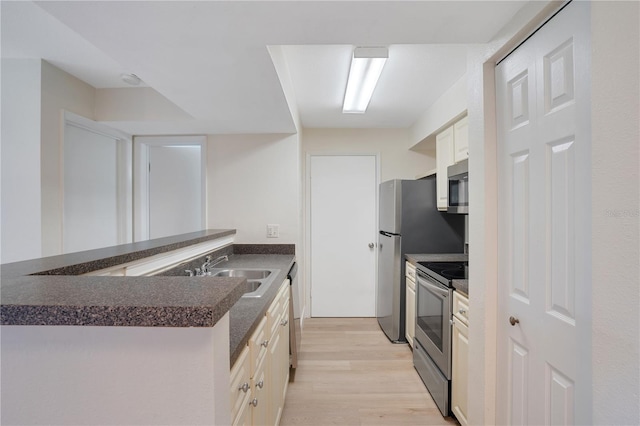 kitchen featuring appliances with stainless steel finishes, sink, light hardwood / wood-style flooring, and kitchen peninsula