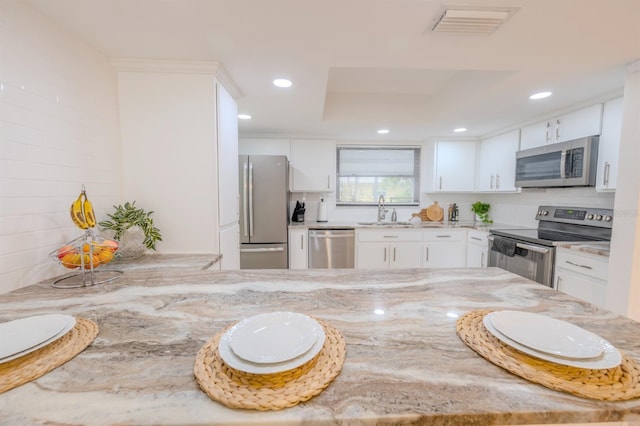 kitchen with light stone counters, white cabinetry, and stainless steel appliances