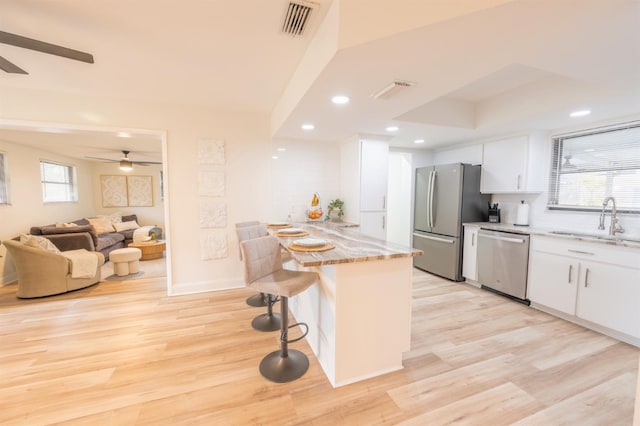 kitchen featuring white cabinets, appliances with stainless steel finishes, sink, and a breakfast bar