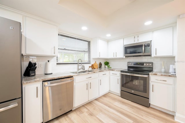 kitchen featuring sink, white cabinets, light wood-type flooring, light stone countertops, and stainless steel appliances