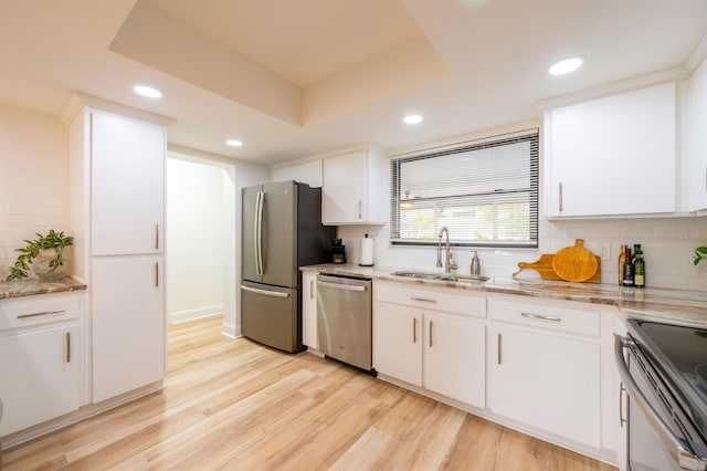 kitchen featuring sink, white cabinetry, a tray ceiling, and appliances with stainless steel finishes