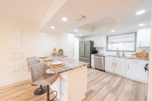 kitchen with decorative backsplash, white cabinets, sink, stainless steel appliances, and light stone counters