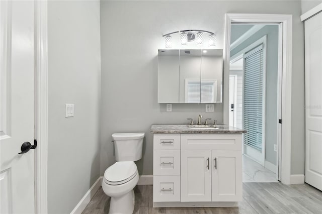 bathroom with hardwood / wood-style flooring, toilet, and vanity