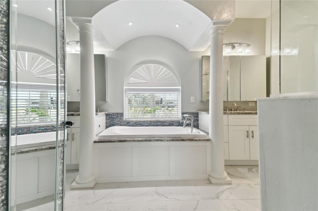 bathroom with decorative columns, vanity, and a bathtub