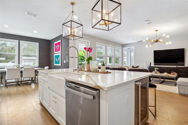 kitchen with pendant lighting, white cabinetry, dishwasher, beverage cooler, and a center island with sink