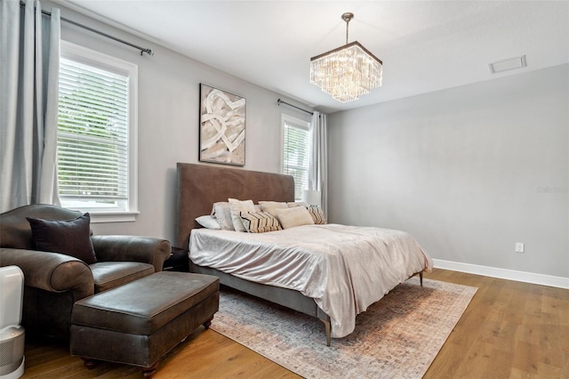 bedroom with an inviting chandelier and wood-type flooring