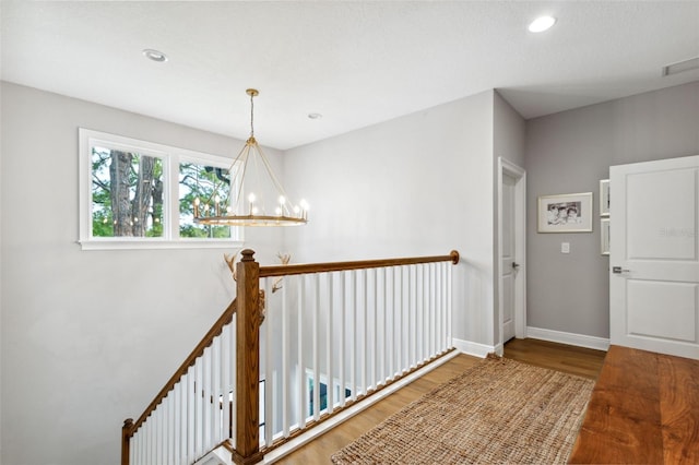 hallway with wood-type flooring and a chandelier