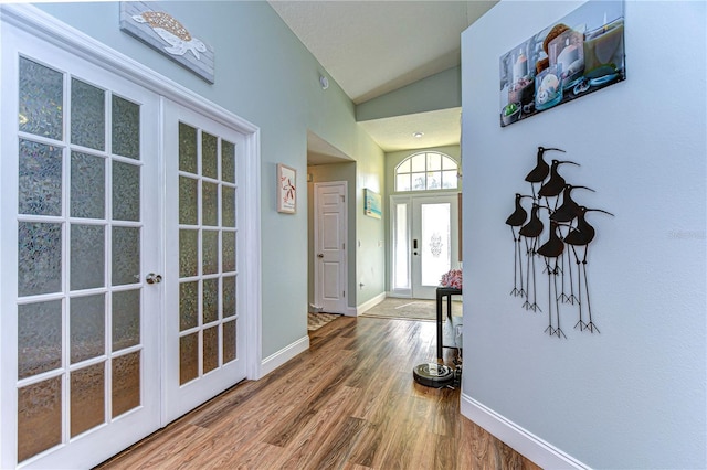 entryway with hardwood / wood-style flooring, vaulted ceiling, and french doors