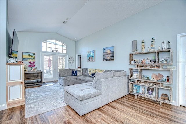 living room with hardwood / wood-style flooring, high vaulted ceiling, and french doors