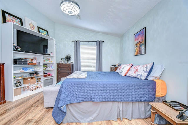 bedroom with vaulted ceiling and light hardwood / wood-style flooring