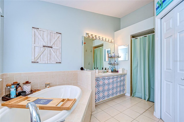 bathroom featuring tile patterned floors, vanity, and tiled bath