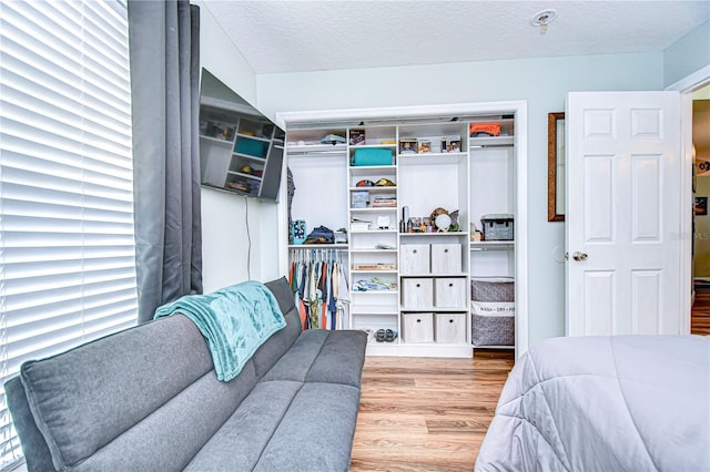 bedroom with a textured ceiling, light wood-type flooring, and a closet