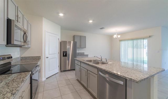 kitchen with sink, hanging light fixtures, a center island with sink, stainless steel appliances, and light tile patterned flooring