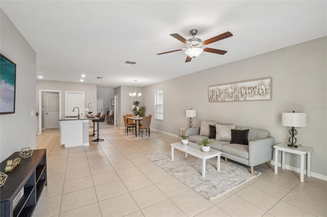 living room with sink, ceiling fan with notable chandelier, and light tile patterned floors