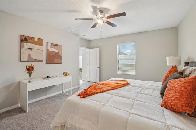 bedroom featuring light carpet, a textured ceiling, and ceiling fan