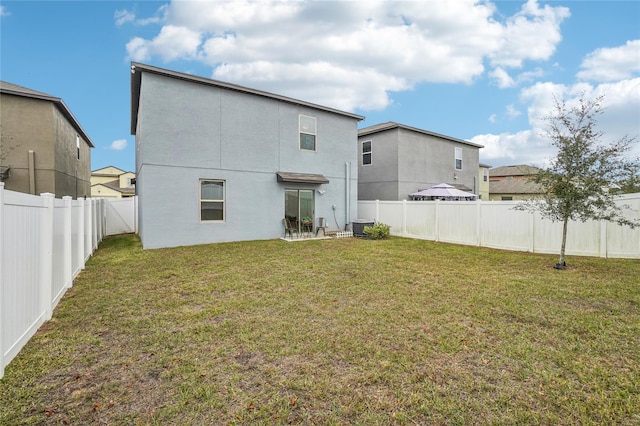 back of house featuring central AC unit and a yard