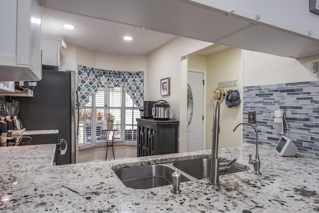 kitchen featuring sink, white cabinets, and light stone countertops