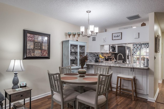 dining area with an inviting chandelier, dark wood-type flooring, and a textured ceiling