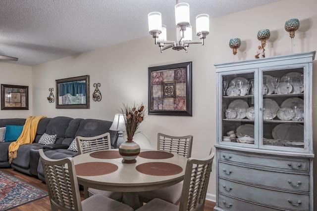 dining space with a textured ceiling, a notable chandelier, and dark hardwood / wood-style flooring