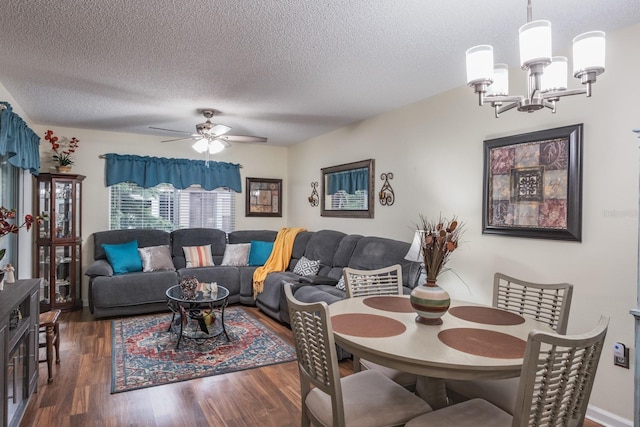 dining space featuring ceiling fan with notable chandelier, dark wood-type flooring, and a textured ceiling