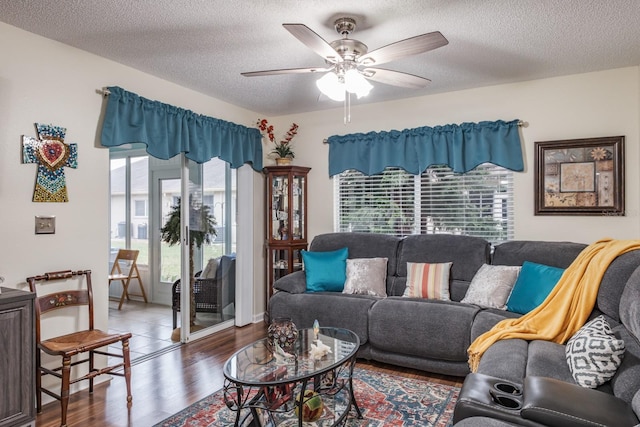 living room with a textured ceiling, dark hardwood / wood-style floors, and ceiling fan