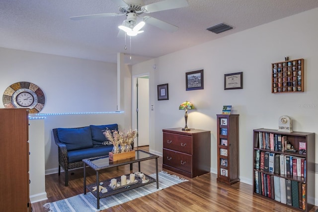 living area with hardwood / wood-style floors, a textured ceiling, and ceiling fan