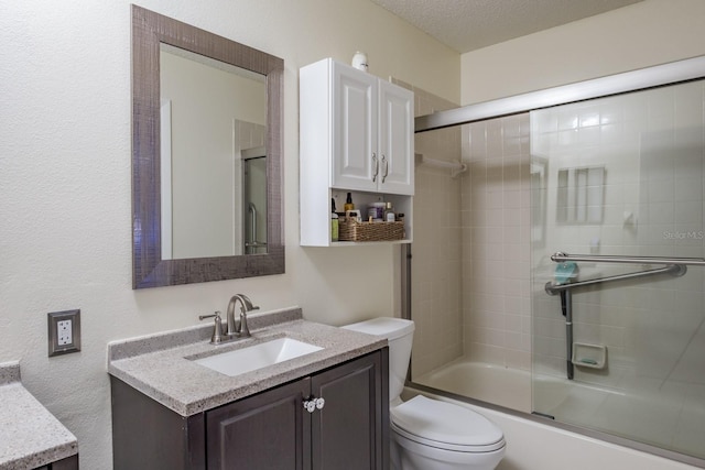 full bathroom featuring a textured ceiling, combined bath / shower with glass door, vanity, and toilet