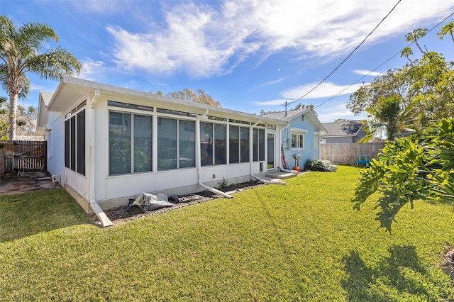 back of house featuring a lawn and a sunroom