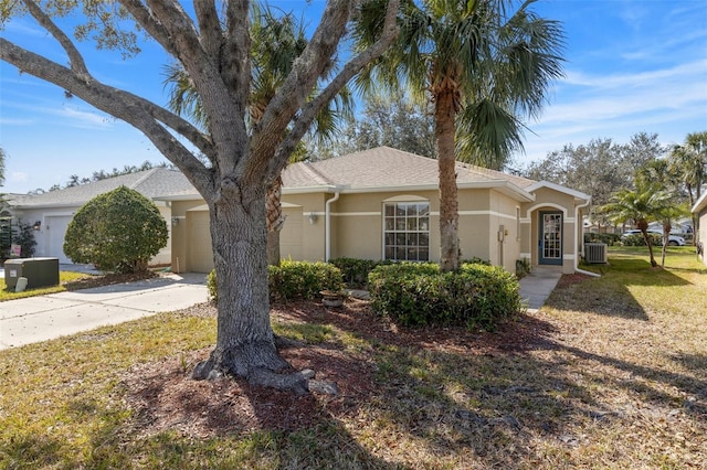 single story home featuring a garage, a front yard, and central air condition unit