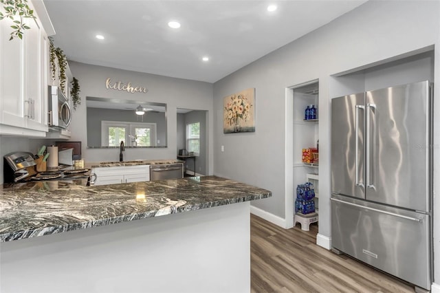 kitchen featuring sink, white cabinetry, stainless steel appliances, and dark stone countertops