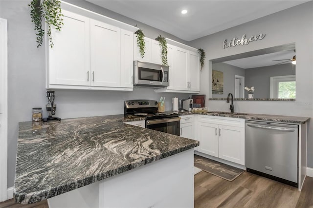 kitchen with kitchen peninsula, sink, white cabinetry, and stainless steel appliances