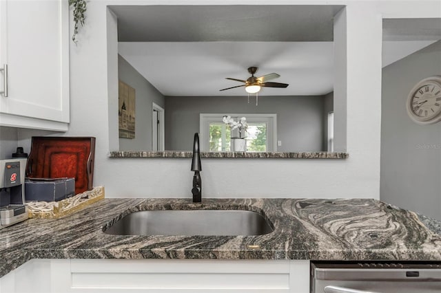 kitchen featuring dishwasher, ceiling fan, sink, white cabinetry, and dark stone counters