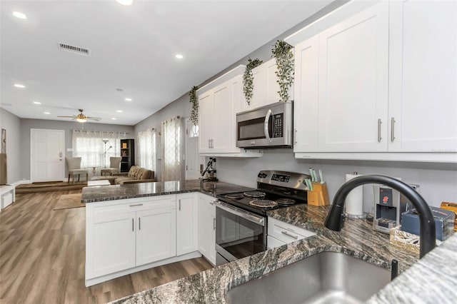 kitchen featuring sink, dark stone counters, white cabinetry, and appliances with stainless steel finishes