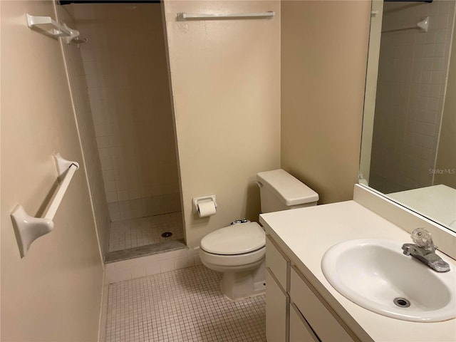 bathroom featuring vanity, a tile shower, tile patterned floors, and toilet