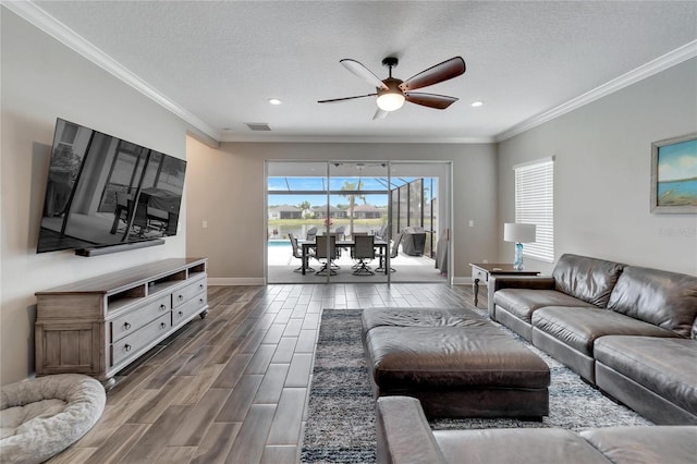 living room featuring ceiling fan, a textured ceiling, and ornamental molding