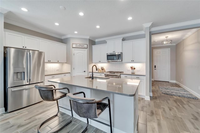 kitchen featuring sink, stainless steel appliances, white cabinetry, and a kitchen island with sink