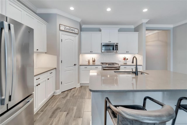 kitchen with light hardwood / wood-style floors, decorative backsplash, white cabinets, sink, and stainless steel appliances