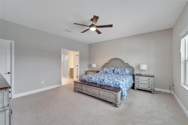 bedroom with ceiling fan, connected bathroom, and light carpet