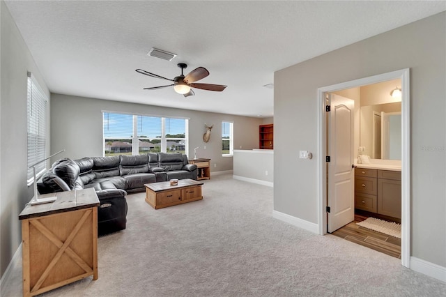 carpeted living room featuring ceiling fan and a textured ceiling