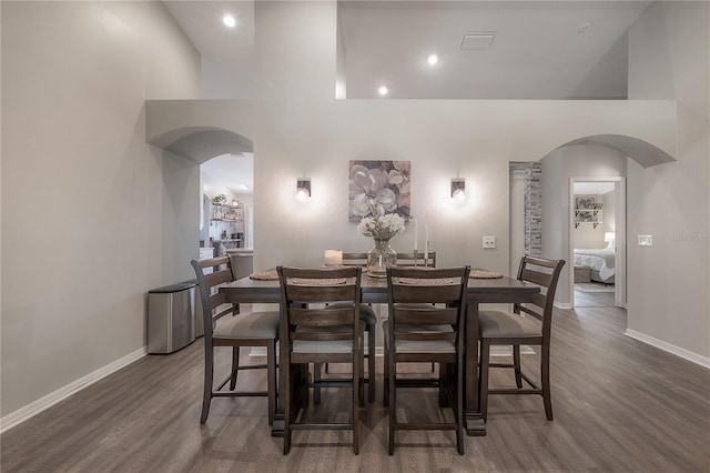 dining room featuring dark hardwood / wood-style floors and a towering ceiling