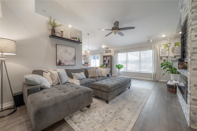 living room with ceiling fan, wood-type flooring, and a stone fireplace