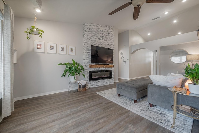 living room with ceiling fan, hardwood / wood-style flooring, a stone fireplace, decorative columns, and lofted ceiling