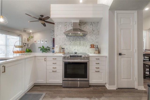 kitchen with stainless steel electric range oven, hanging light fixtures, white cabinetry, and wall chimney range hood