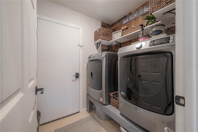 clothes washing area featuring a textured ceiling, washing machine and dryer, and light tile patterned floors