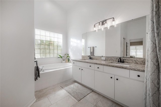 bathroom featuring a towering ceiling, tile patterned flooring, tiled tub, and vanity